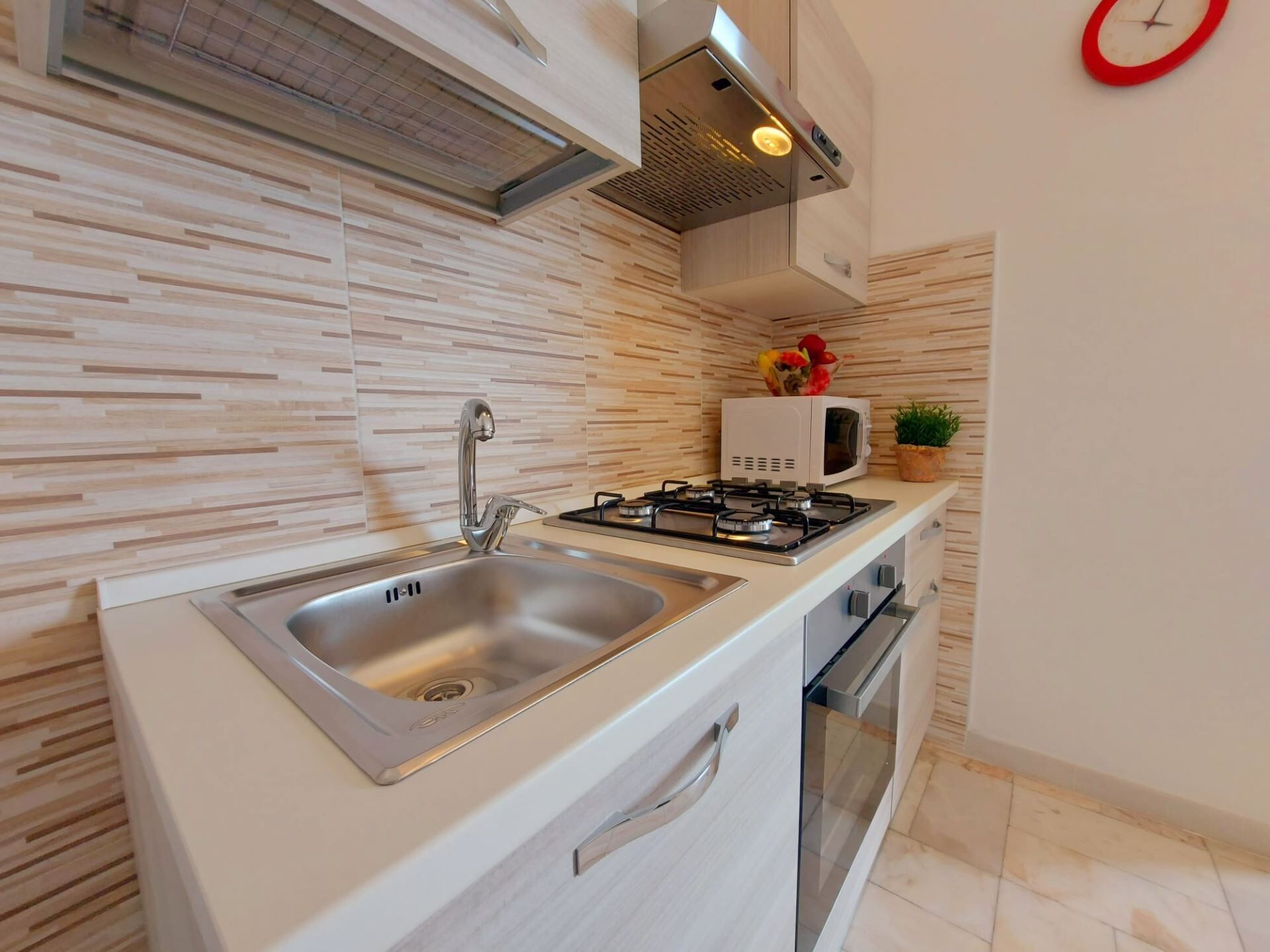 A modern kitchen with a stainless steel sink, a gas stove, and a microwave.