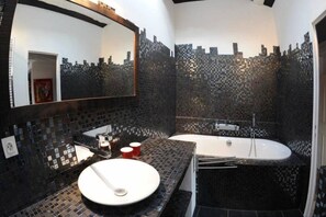 Une salle de bain moderne avec un grand miroir, une baignoire et un lavabo.