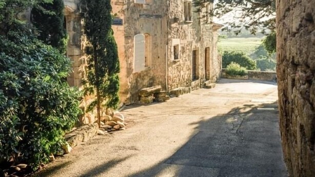 A narrow street flanked by stone buildings with arched windows and a clear sky. - Village house with heated pool in the Luberon for 14 people (Ansouis)