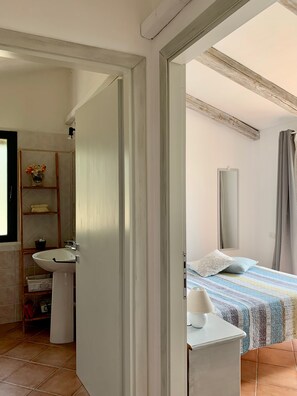 Een badkamer met een wastafel, spiegel en planken met toiletartikelen.