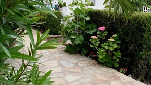 A stone pathway leading through a garden with various plants and flowers. - CHARMING HOUSE (Le Pouliguen)