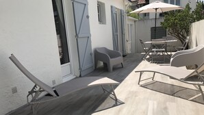 A patio with two lounge chairs, a small table, and a white umbrella. - CHARMING HOUSE (Le Pouliguen)