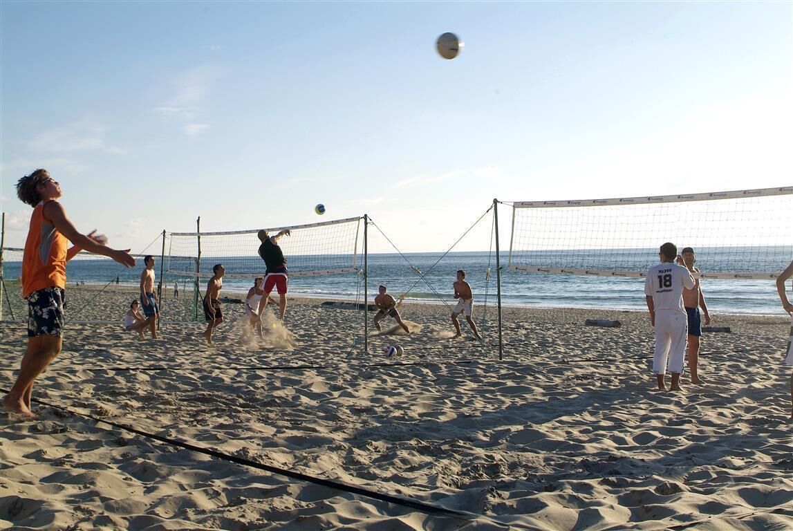 A beach volleyball game with players in casual beachwear.