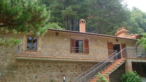 Un bâtiment en pierre doté d’un balcon, d’un escalier et d’une cheminée.
