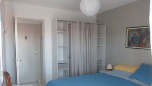 A bedroom with a bed, a chair, a wardrobe, and a painting on the wall.