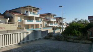 A row of residential buildings with balconies, a clear sky, and a streetlight.