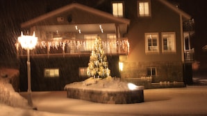 A snow-covered building with a Christmas tree and string lights. - Newly built, high-quality holiday home close to Viksdalsvatnet — sleeps 9 (Viksdalen)