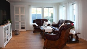 A living room with a brown leather sofa set, a white cabinet, and a glass-fronted cabinet. - Newly built, high-quality holiday home close to Viksdalsvatnet — sleeps 9 (Viksdalen)