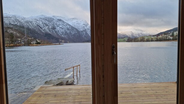 A wooden deck with a view of a lake and snow-covered mountains. - Newly built, high-quality holiday home close to Viksdalsvatnet — sleeps 9 (Viksdalen)