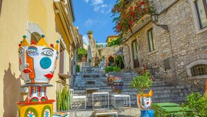 Una stretta via fiancheggiata da edifici in pietra e sculture colorate e fantasiose.