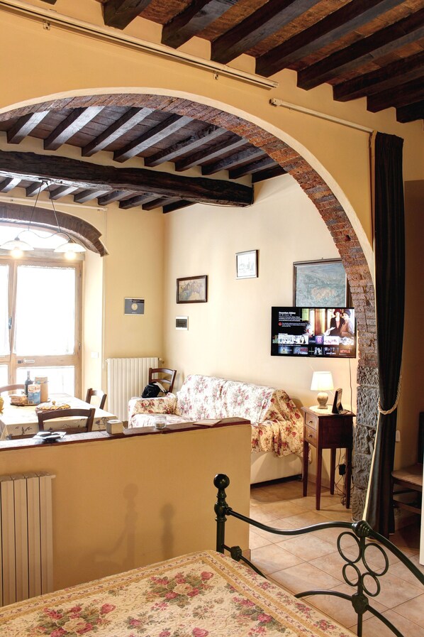 A room with a bed, a table, a chair, a TV, and a window.
