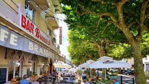 An outdoor cafe area with tables and chairs, surrounded by trees and a building with a sign that reads "BAR BRASSERIE DU CENTRE". - Superb 19th C. Farmhouse in extensive grounds, near Pyrenées, Pau and Lourdes (Caixon)