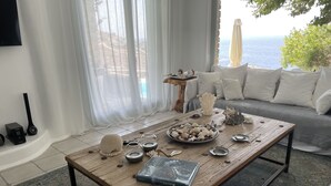 Ein Wohnzimmer mit Couch, Holztisch und Meerblick.