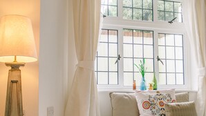 Un rincón acogedor con una lámpara, una ventana con cortinas y vistas al exterior.