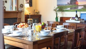 Mesa de café da manhã para duas pessoas, com croissants, frutas e suco.
