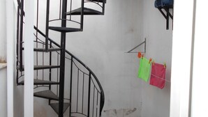 Eine Wendeltreppe in einem Raum mit weißen Wänden, einer sichtbaren Fleck und einer Wäscheleine mit zwei Kleidungsstücken.