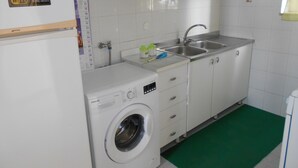 Eine kleine Küche mit Waschmaschine, Spüle und Schränken.