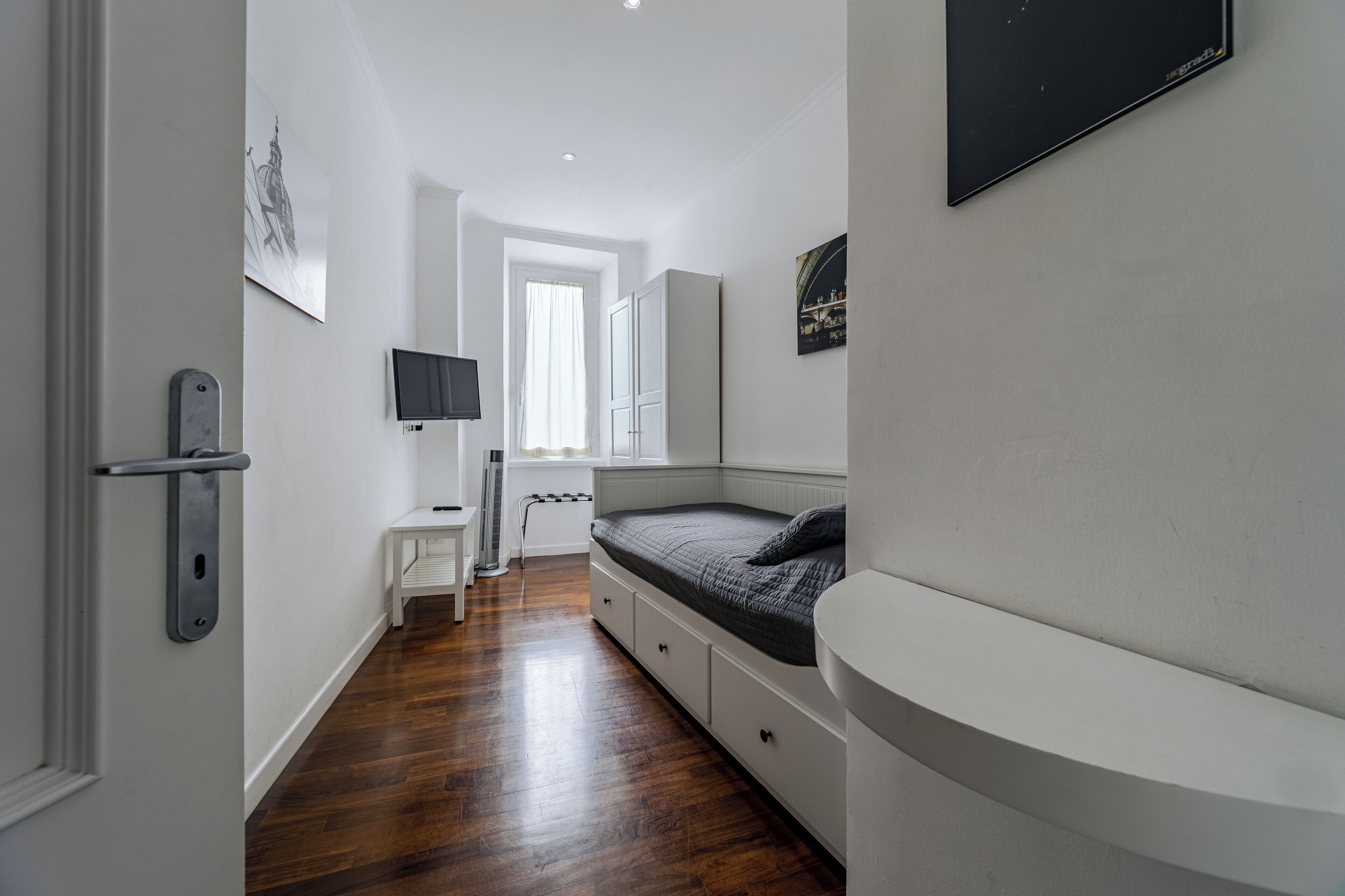 A bedroom with a bed, a desk, and a TV.