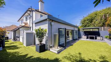 A modern house with a well-maintained lawn, a patio area, and a large window overlooking the yard.