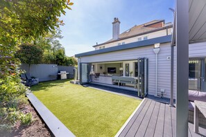 A modern house with a patio, a lawn, and a TV in the living area.
