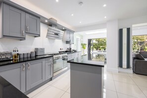 A modern kitchen with grey cabinets, a central island, and a view of the outdoors.