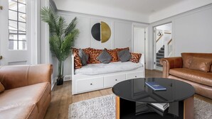 A modern living room with a sofa, a coffee table, and a large plant.