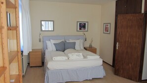 Une chambre à coucher avec un lit, des tables de chevet, une armoire en bois et une fenêtre.