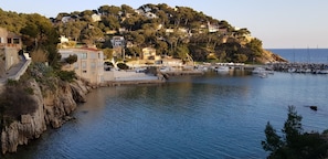 A coastal town with buildings on a hillside, a marina with boats, and a rocky shoreline. - The creeks, the sea, the hikes and a beautiful apartment with swimming pool. (Ensuès-La-Redonne)