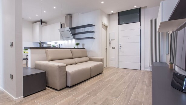 A modern living room with a sofa, a small table, and a kitchen area in the background. -  Civico 88 Modern design (Padova)