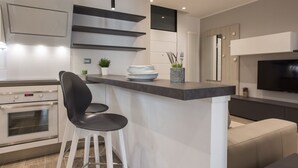 A modern kitchen with a built-in oven, a bar area with stools, and a flat-screen TV mounted on the wall. -  Civico 88 Modern design (Padova)