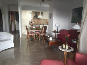 Habitación de hotel con comedor, sala de estar con sofá, una lámpara y un cuadro en la pared.