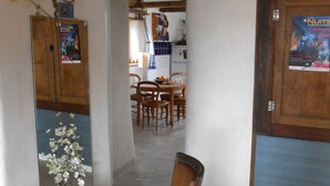 A dining area with a wooden chair, a table, and a kitchen in the background. - The Lily Féliz, a pretty village house between Rodez and Albi (Centrès)
