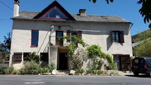 A two-story house with a stone facade, a red-tiled roof, and a small balcony with metal railings. - The Lily Féliz, a pretty village house between Rodez and Albi (Centrès)