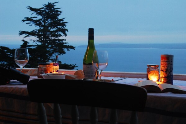 Une table dressée pour deux personnes, avec une bouteille de vin, deux verres, une bougie et un pot de crème.