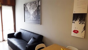 A modern living room with a black leather sofa, a wooden coffee table, and a wall-mounted calendar.