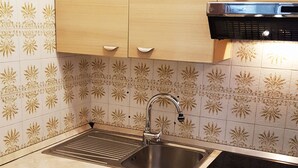 A kitchen with two sinks, a stove, and light wooden cabinets.