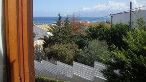 Vista costera con un marco de ventana de madera, una valla blanca y un edificio con techo rojo.