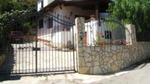 Una casa de dos pisos con un muro de piedra y una reja de metal.