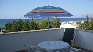 Un balcón con mesa y sillas, con vistas a la costa.