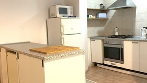 A compact kitchen with a microwave, stove, oven, and a small countertop.