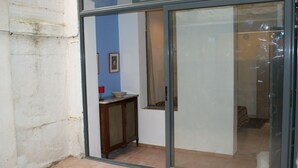 A room with a sliding glass door leading to a balcony, a small table with a bowl, and a framed picture on the wall.