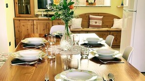Mesa de comedor dispuesta para seis personas, con platos, cubiertos y un jarrón de flores.