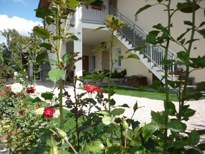 A building with a staircase leading to a second floor, surrounded by a garden with roses. - Relaxing holiday - mountain, lake and spa (Barco)
