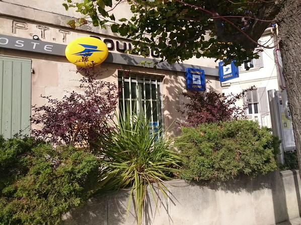 A building with a postal sign, a mailbox, and a small plant in front.