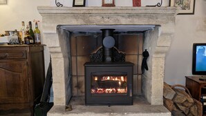 A stone fireplace with a modern wood-burning stove, a clock, and a framed picture above it.