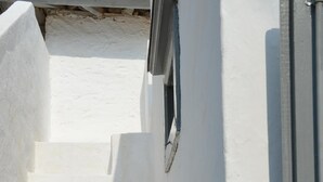 Una serie di gradini bianchi che conducono a una porta, con un'ombra proiettata sul muro.