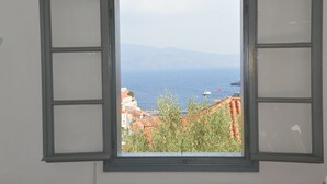 Una finestra con vista sul mare e sugli edifici.