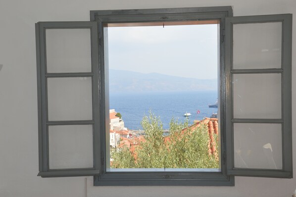 A window with a view of the sea and buildings. - Hydra studio house with amazing harbour views (Hydra Town, Hydra)