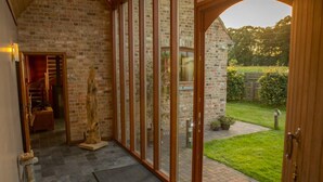 A hallway with a brick wall, a wooden door, and a view of a garden.