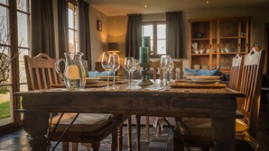 A dining table set with glasses, a pitcher, and a candle.